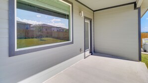 Un bâtiment moderne doté d’une grande fenêtre, d’une porte et d’un patio en béton.