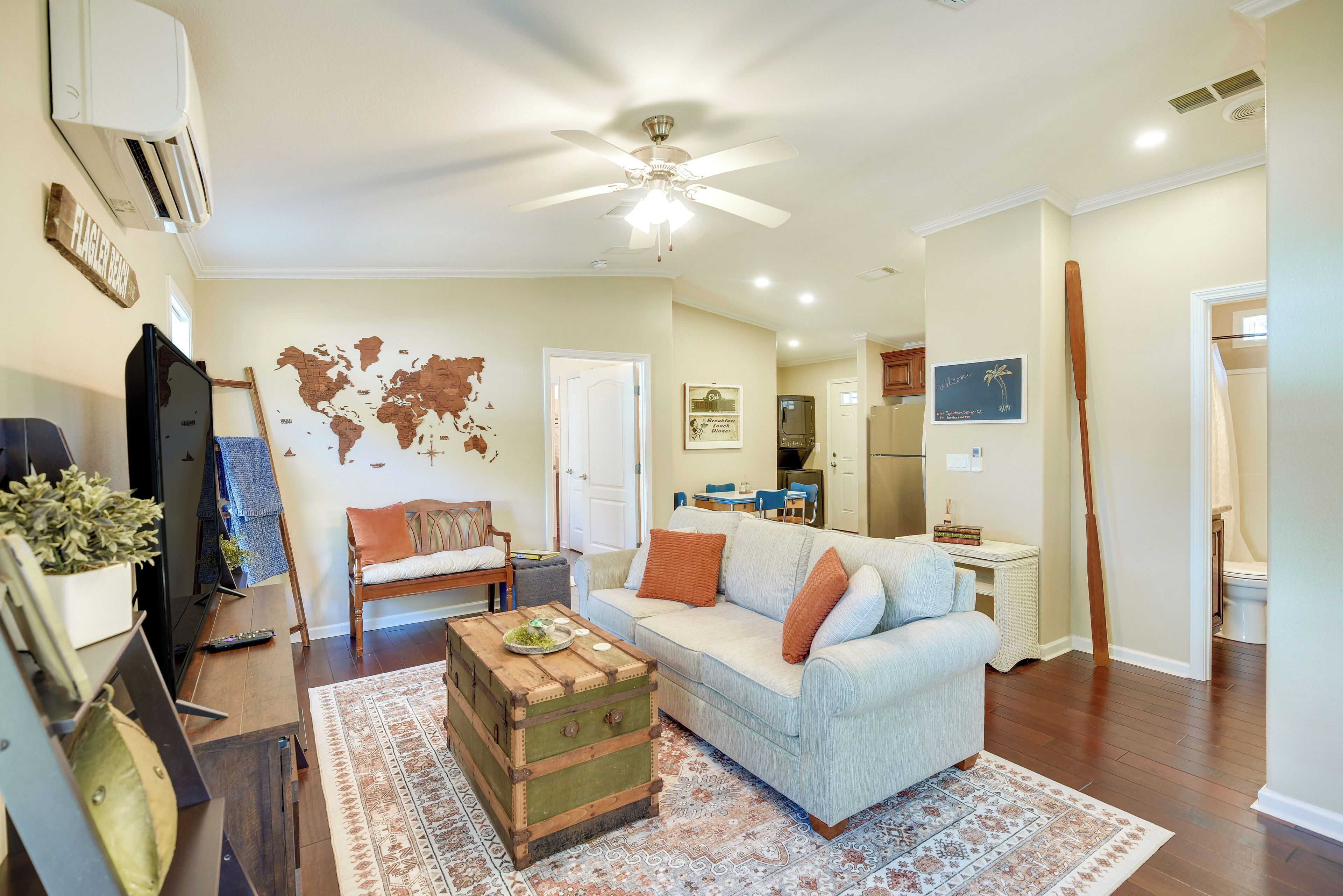 A living room with a sofa, a coffee table, a world map on the wall, and a ceiling fan.