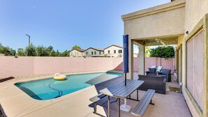 A backyard with a swimming pool, outdoor furniture, and a covered patio area. - Spacious Surprise Home w/ Outdoor Pool + Game Room (Surprise)