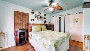 A bedroom with a bed, a ceiling fan, a wooden barrel, and a door with a sign. - Waterfront Key West Oasis w/ Float Dock! (Key West)