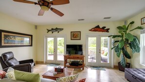A living room with a leather sofa, a coffee table, a TV, and a large plant. - Waterfront Key West Oasis w/ Float Dock! (Key West)