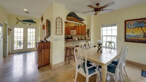 A spacious kitchen with wooden cabinets, a dining area with white chairs, and a ceiling fan. - Waterfront Key West Oasis w/ Float Dock! (Key West)