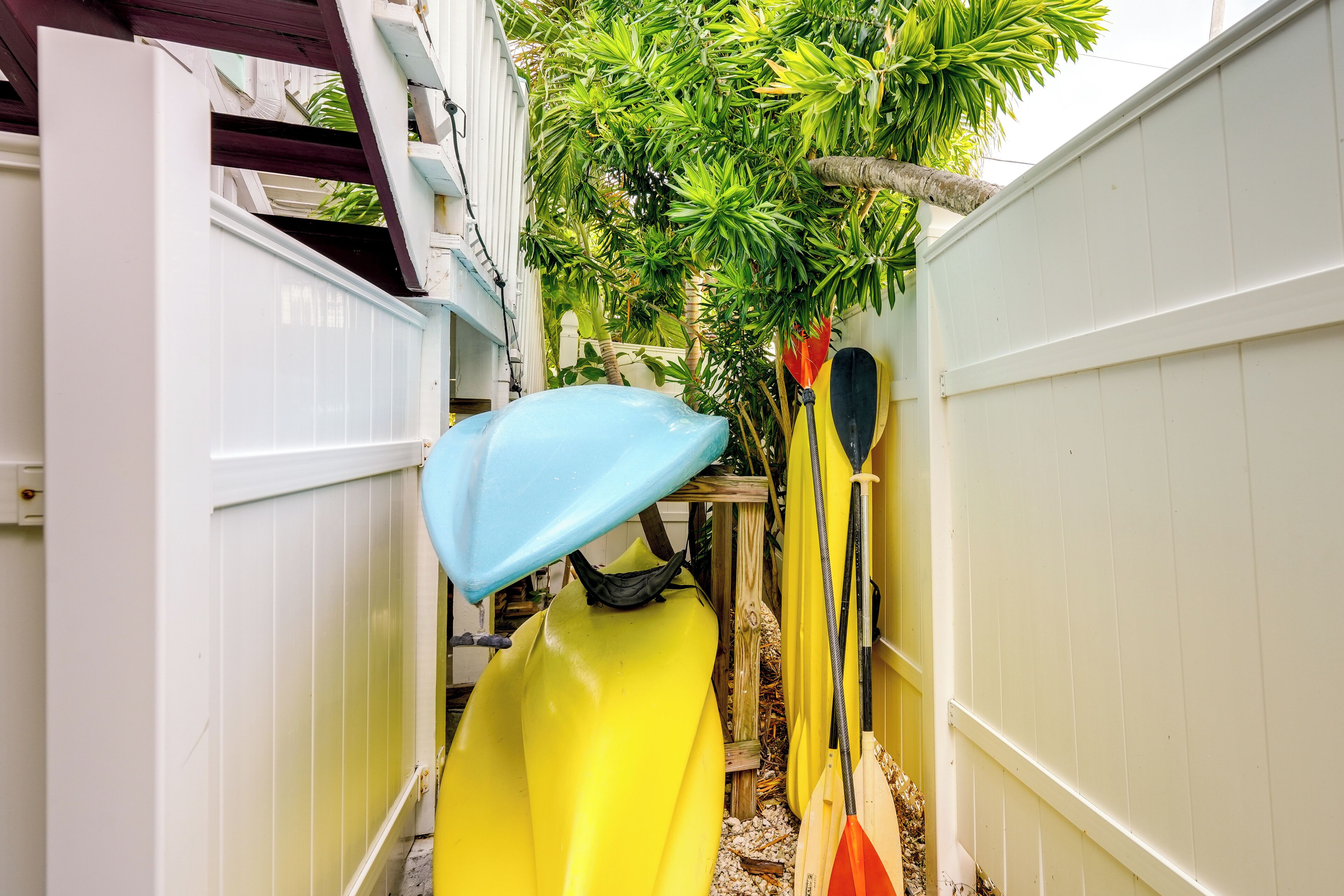 A narrow outdoor space with a yellow kayak and a blue tarp.