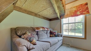 Une pièce d’angle avec un canapé, une fenêtre et un plafond en bois.