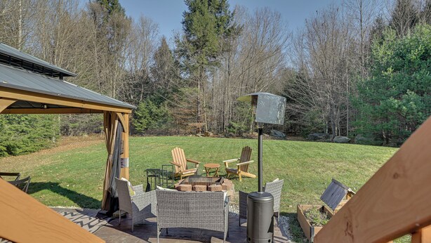 Une terrasse dotée de meubles en osier, d’un foyer extérieur et d’une pergola.