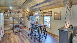 Une cuisine rustique avec un plancher en bois, un îlot central doté de tabourets et un luminaire suspendu.