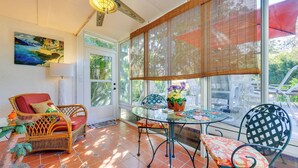 A sunlit patio with wicker furniture, a glass table, and a view of the outdoors. - Serene St Augustine Townhome: Walk to Beach! (St. Augustine)