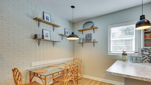 A kitchen with a wooden table and chairs, a window with blinds, and wall-mounted shelves with decorative items. - Beachy Wilmington Home: 6 Mi to Riverwalk + Dtwn! (Wilmington)