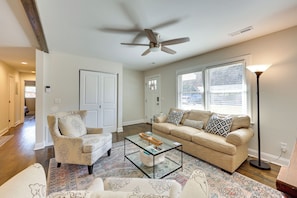 A living room with a beige sofa, a glass coffee table, a patterned rug, and a ceiling fan. - 4 Mi to Beach: Wilmington Home w/ Gazebo Deck! (Wilmington)