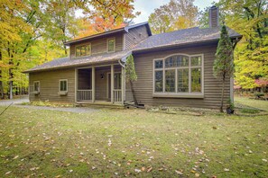 A two-story house with a front porch, a covered garage, and a small front yard with scattered leaves. - Family-friendly Home in Sturgeon Bay w/ Backyard (Sturgeon Bay)