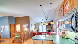 A kitchen with wooden cabinets, a stove, and a dining area with a table and chairs. - Burnside Resort Cabin w/ Hot Tub & Outdoor Spots! (Burnside)
