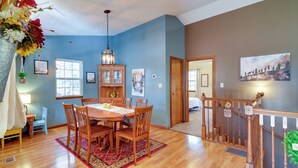 A dining area with a wooden table and chairs, a hanging light fixture, and a red rug. - Burnside Resort Cabin w/ Hot Tub & Outdoor Spots! (Burnside)