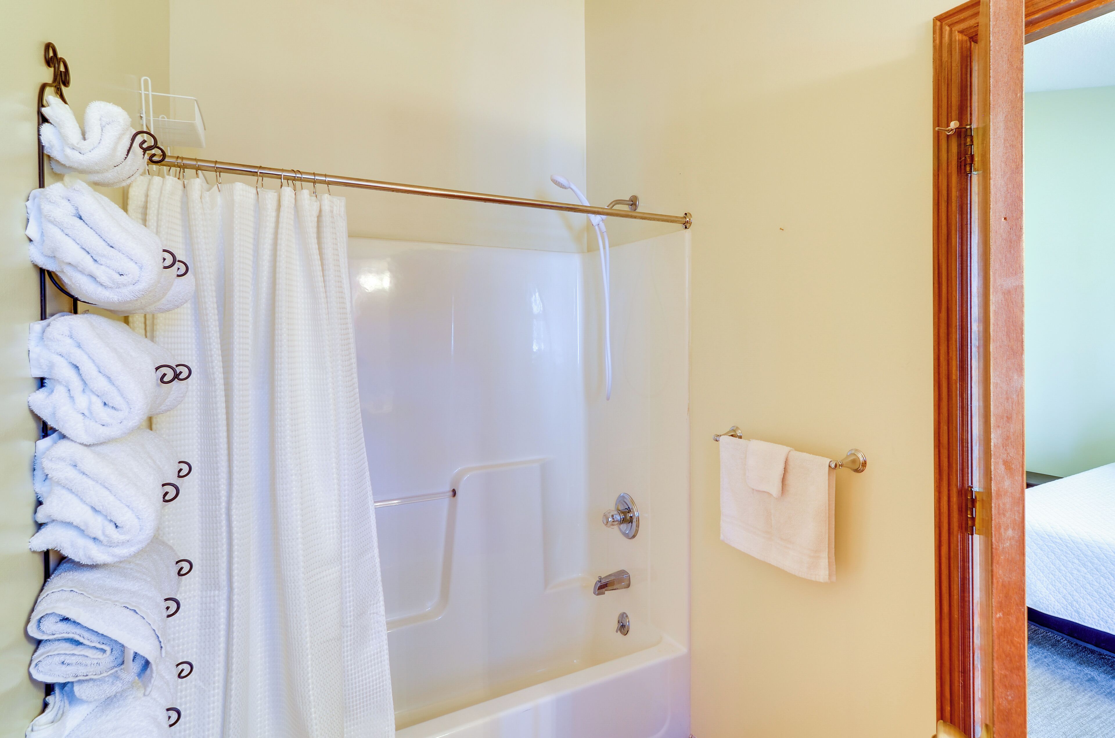 Ein Badezimmer mit einer Badewanne, einer Duschvorhang und einem Handtuchhalter mit mehreren Handtüchern.