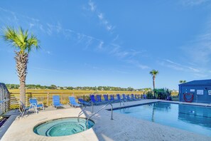 A pool area with blue lounge chairs, a hot tub, and palm trees. - Murrells Inlet Condo w/ Balcony & Pool: Near Pier! (Murrells Inlet)