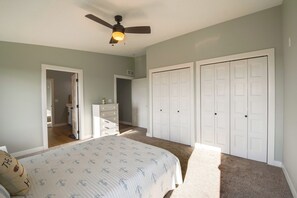 A bedroom with a bed, a ceiling fan, a dresser, and a closet. - Views of Lewis & Clark Lake - Modern Apt w/ Deck (Crofton)