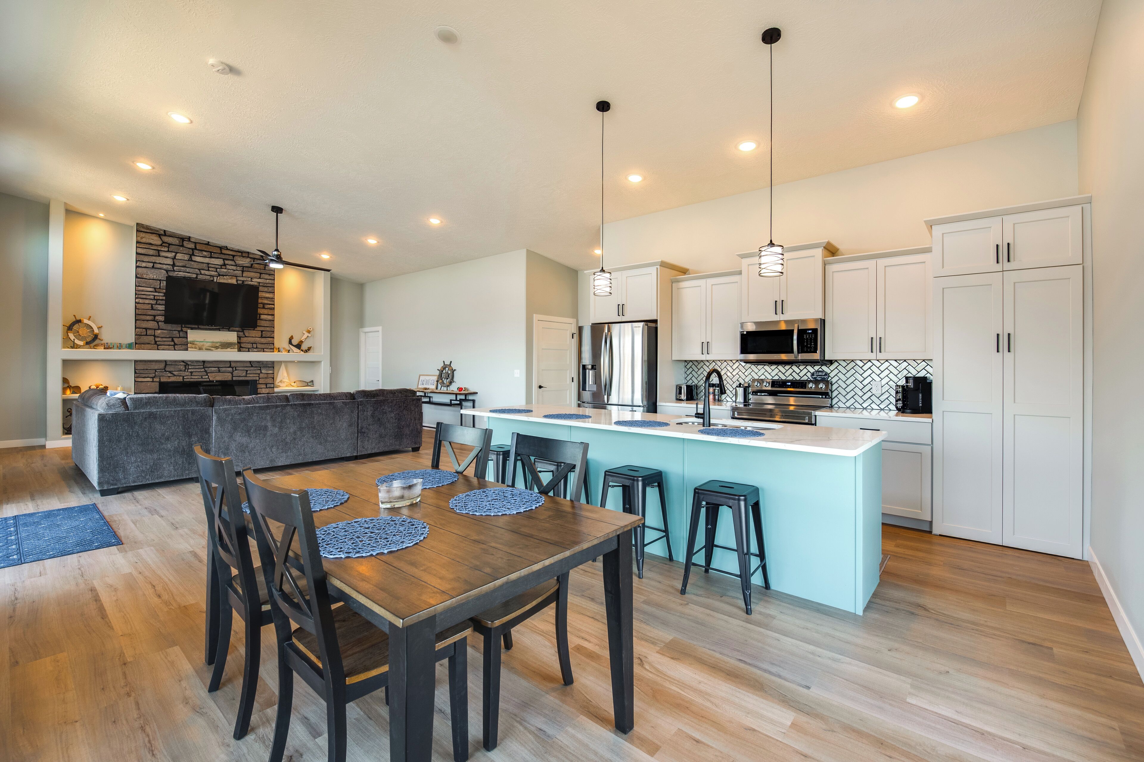 A modern kitchen with a central island, built-in appliances, and a dining area with a wooden table and chairs.