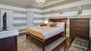 Un dormitorio con cama, cómoda, televisor y candelabro.