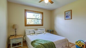 A bedroom with a bed, a nightstand, a window, a picture on the wall, and a basket of flowers. - Charming Rockland Retreat w/ Deck & Grill! (Bangor)
