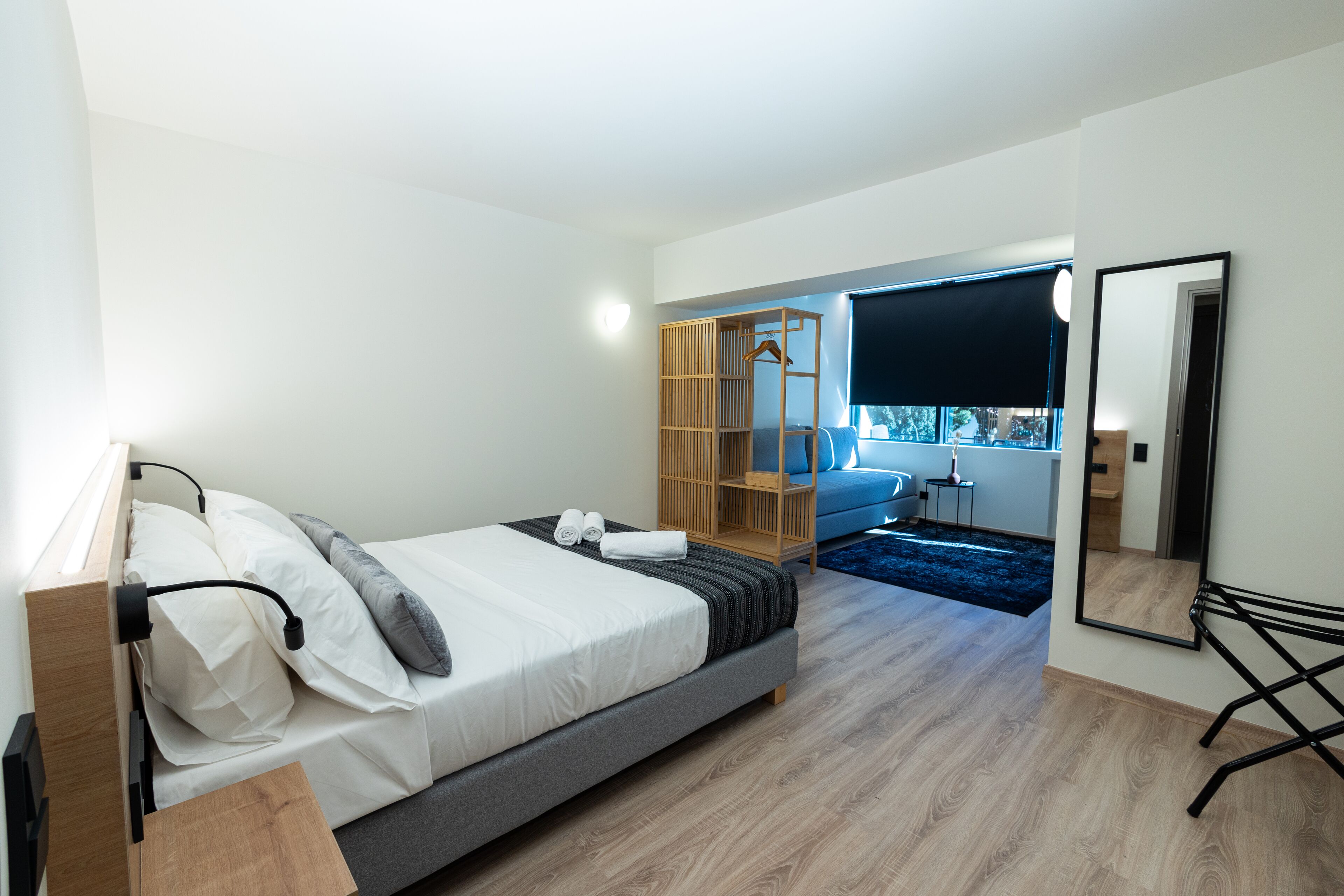 Un dormitorio moderno con cama, mesita de noche, armario y un espejo grande.