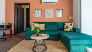 Una sala de estar con un sofá verde azulado, una mesa de centro redonda y tres obras de arte enmarcadas en la pared.