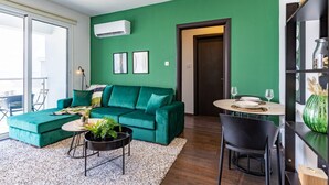 Een moderne woonkamer met een groene bank, een eettafel en een zwarte stoel.
