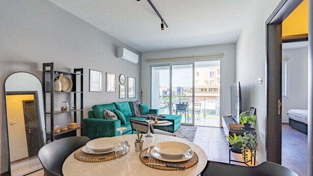A modern living room with a dining area, a sofa, and a TV. - Harbor 102: Stylish 1-Bedroom Apartment in Larnaca (Cyprus - Larnaca)
