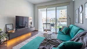 Una sala de estar moderna con un televisor de pantalla plana, un sofá verde y un comedor con mesa y sillas.