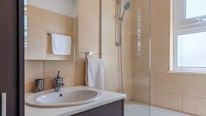 Un baño moderno con cabina de ducha de vidrio, un lavabo blanco y una bañera.