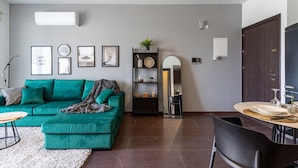 Una sala de estar moderna con un sofá color turquesa, una mesa de centro y un comedor con una mesa redonda y sillas.