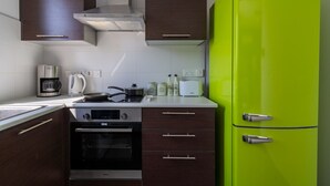 Una cocina con estufa moderna, horno y un refrigerador verde brillante.