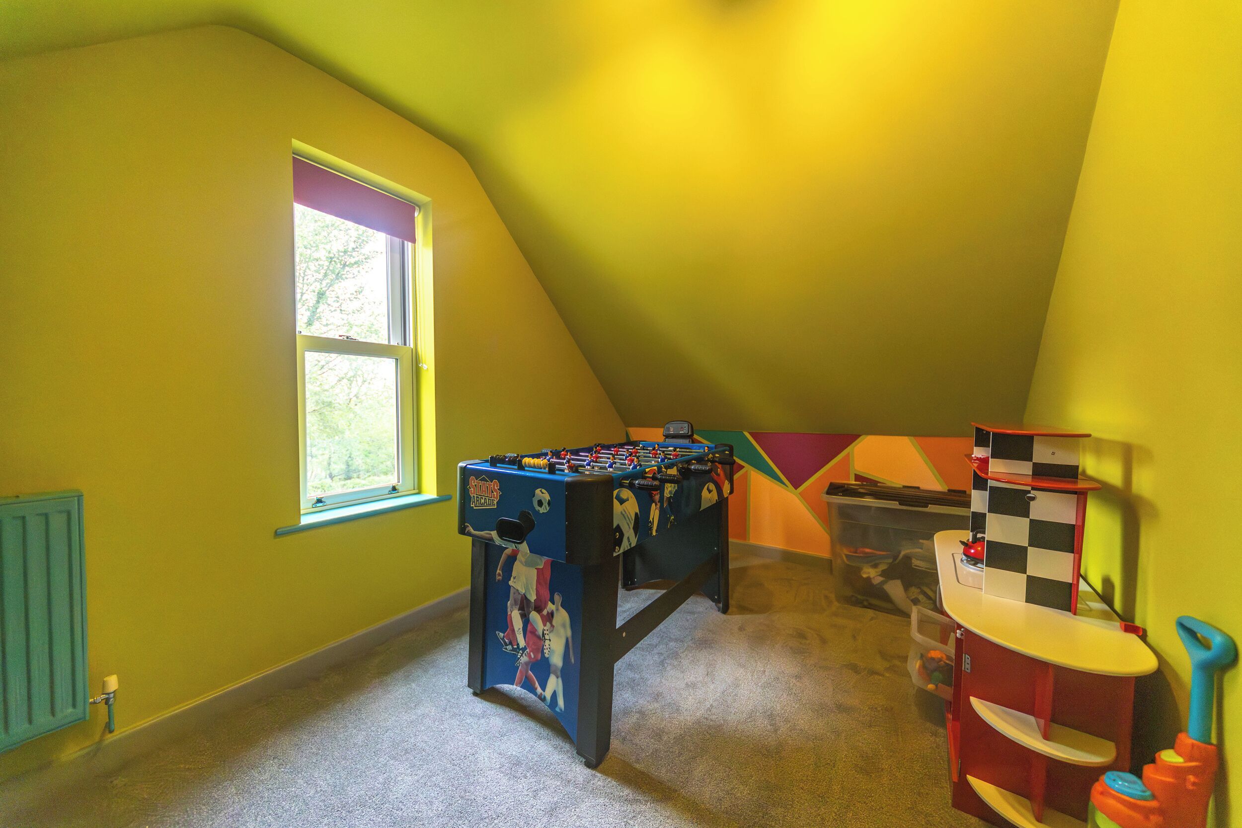 A room with a foosball table, a small table with checkered cloth, and a window.