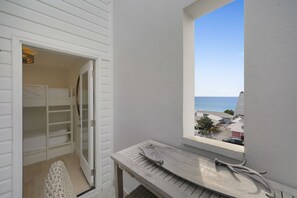 A balcony with a view of the beach, a white door, and a small table with a tray.