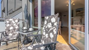 A balcony with two chairs, a table, and a glass door leading to an interior space. - Ferienwohnung am Meer, Urlaub auf der Insel Usedom, Apartment Bianco 49 (Świnoujście)