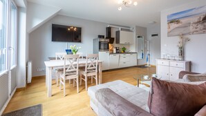 A modern apartment with a dining area, kitchenette, and a living room with a sofa and a TV. - Ferienwohnung am Meer, Urlaub auf der Insel Usedom, Apartment Bianco 49 (Świnoujście)