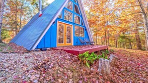 A blue cabin with a steep roof, a red door, and a small porch with two chairs. - A-Frame of Mind - Time to Kick Back and Relax (Demorest)