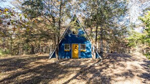 A cabin with a triangular roof, surrounded by trees and a dirt path. - A-Frame of Mind - Time to Kick Back and Relax (Demorest)
