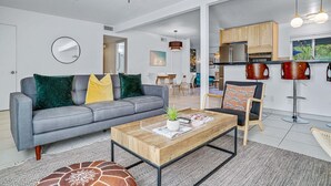 Un salon moderne avec un canapé gris, une table basse en bois et un ventilateur de plafond.