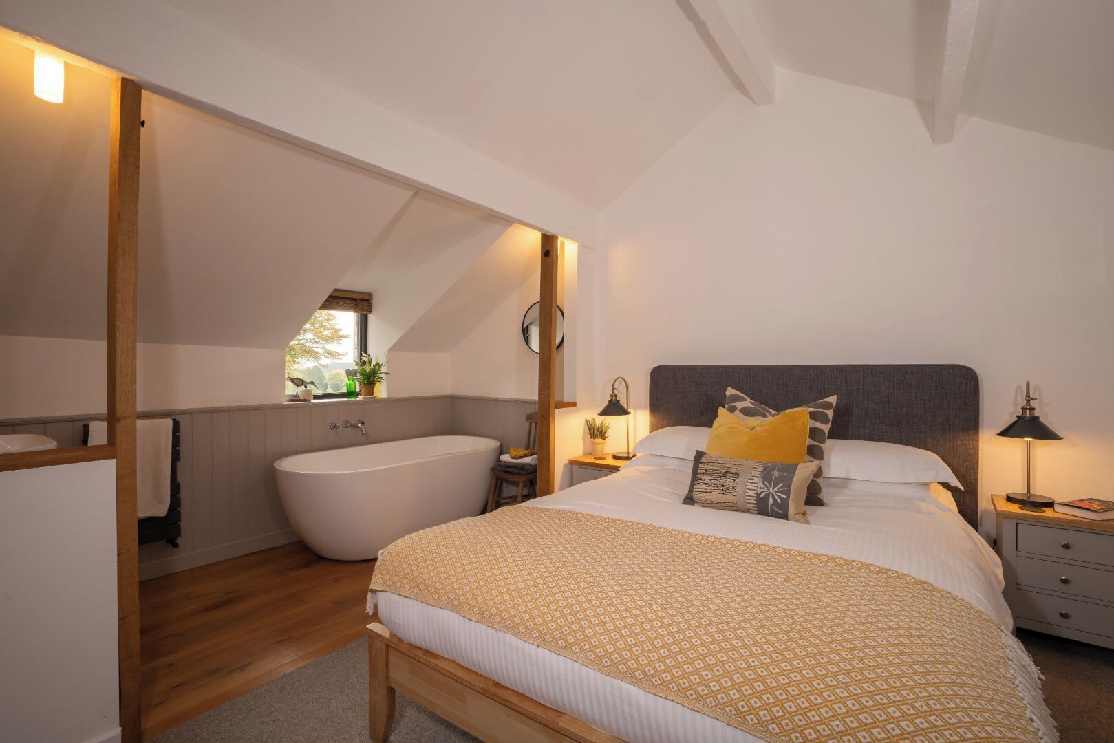 Une chambre avec un grand lit, une baignoire intégrée et une table de chevet avec une lampe.