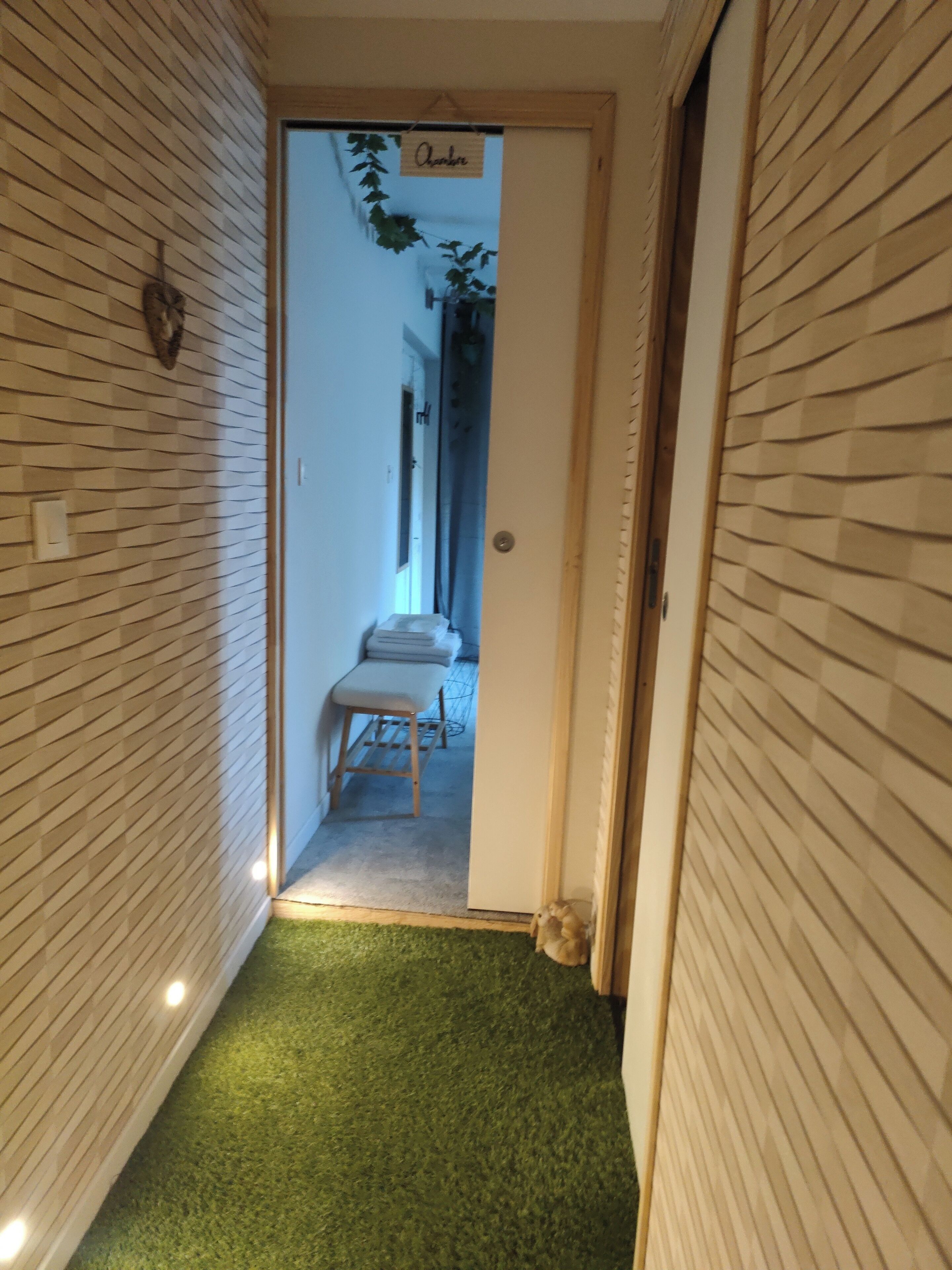 A narrow hallway with wooden paneling on the walls, a bench, and a small table.