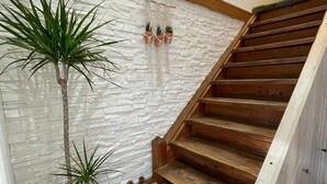 Eine Holztreppe mit einer weißen, strukturierten Wand und einer schwarzen Matte am Fuß.
