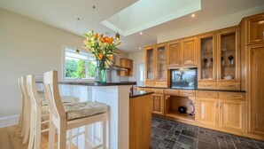 A modern kitchen with wooden cabinets, a central island, and a vase of flowers.