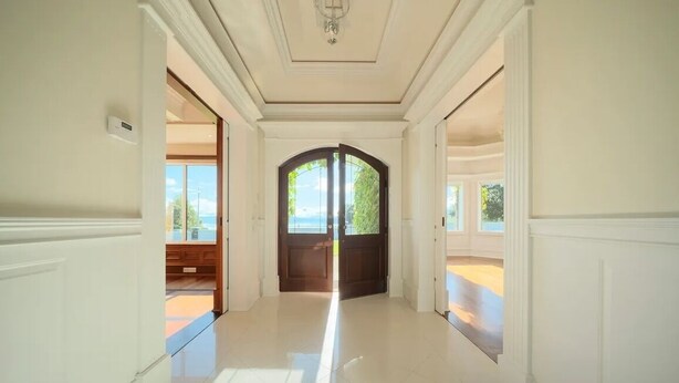 A hallway with white walls and a wooden door at the end.