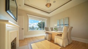 A spacious room with a fireplace, a dining area with chairs, a large window, and a ceiling light fixture.