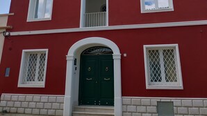 A red building with white trim, multiple windows, and a green door. - RMaison Luxury Suites Olbia  (Olbia)