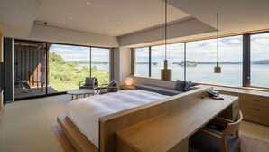 Un dormitorio moderno con una cama grande, un escritorio y vistas a un lago.