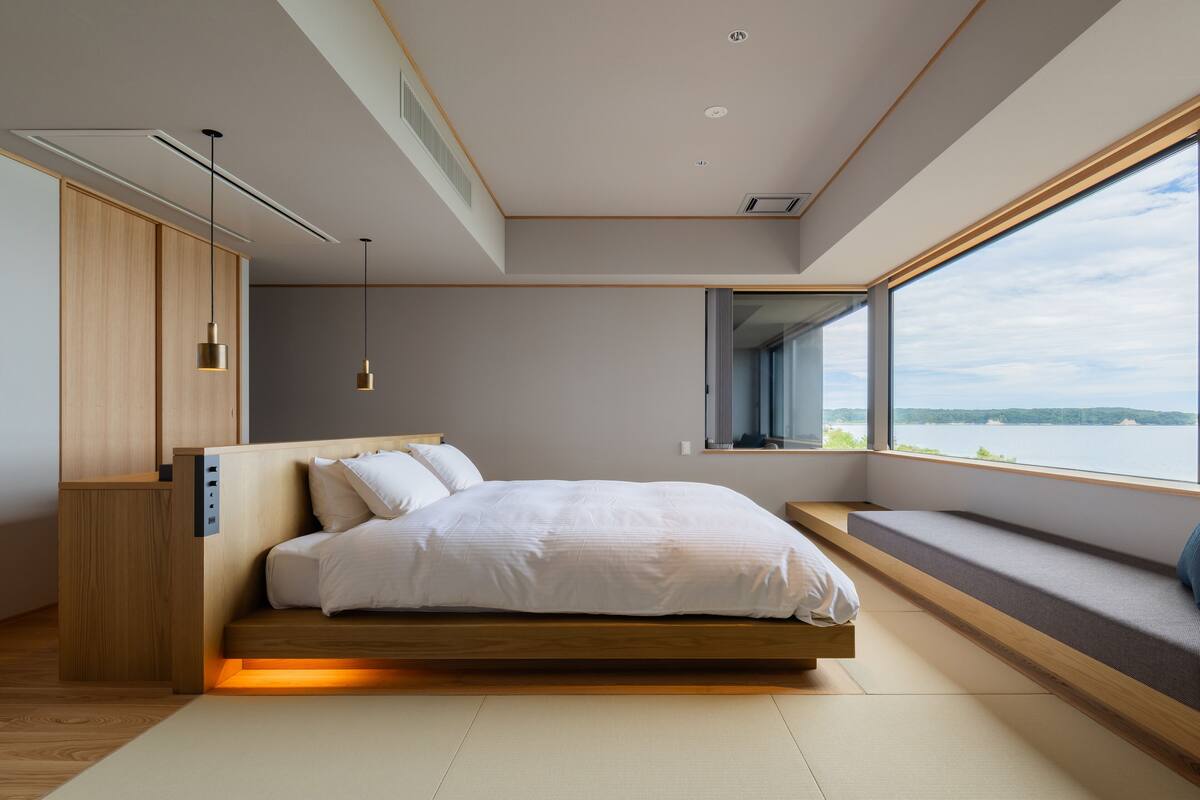 A modern bedroom with a built-in bed, bedside storage, a window with a view, and a ceiling with recessed lighting.