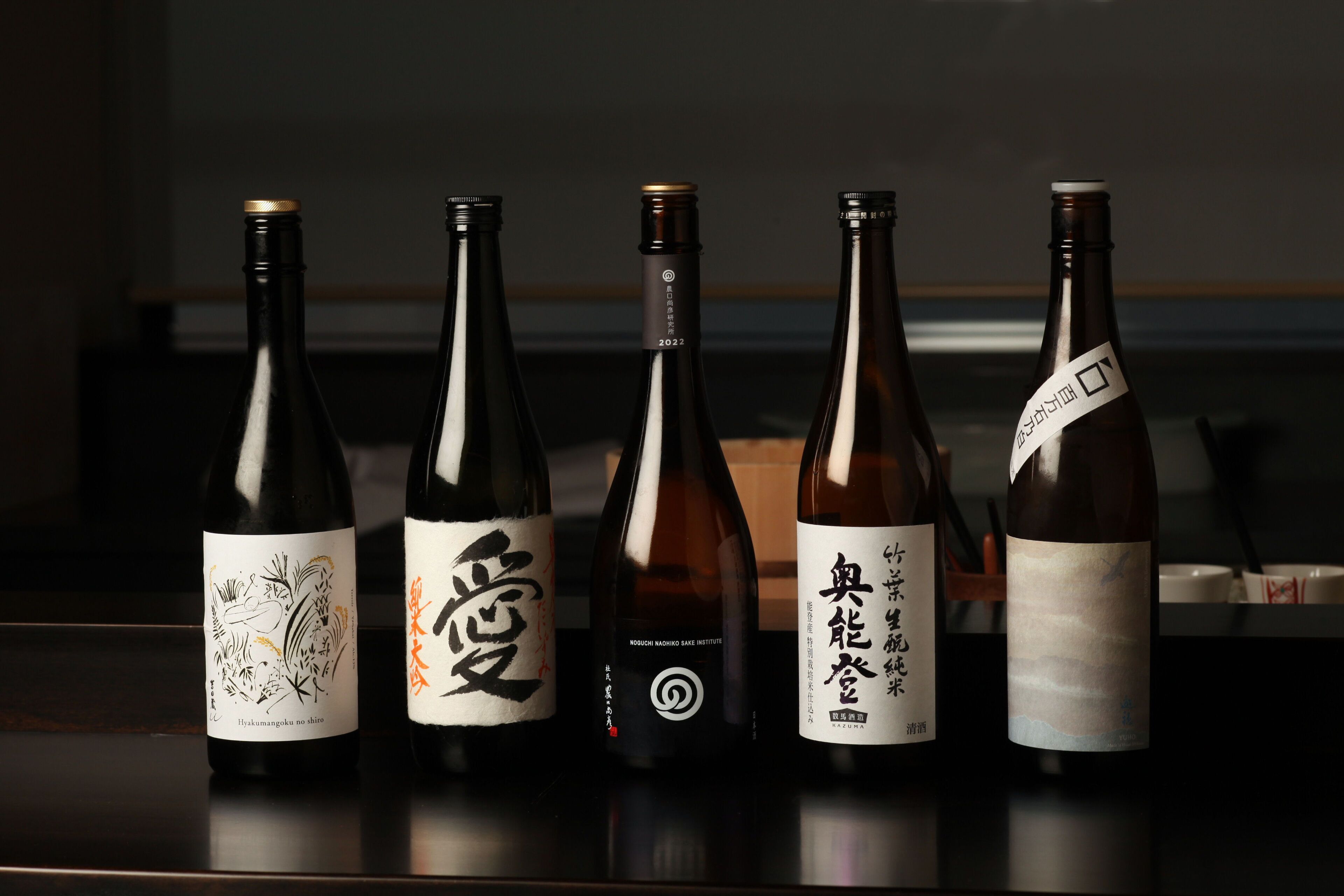Cinco botellas de sake dispuestas sobre una mesa.