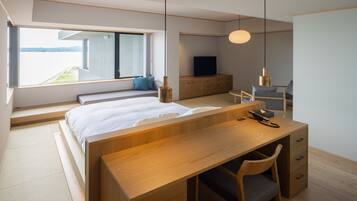 A modern bedroom with a large bed, wooden desk, and a view of the outdoors.