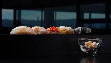 A sushi platter with various pieces on a black table against a windowed background.