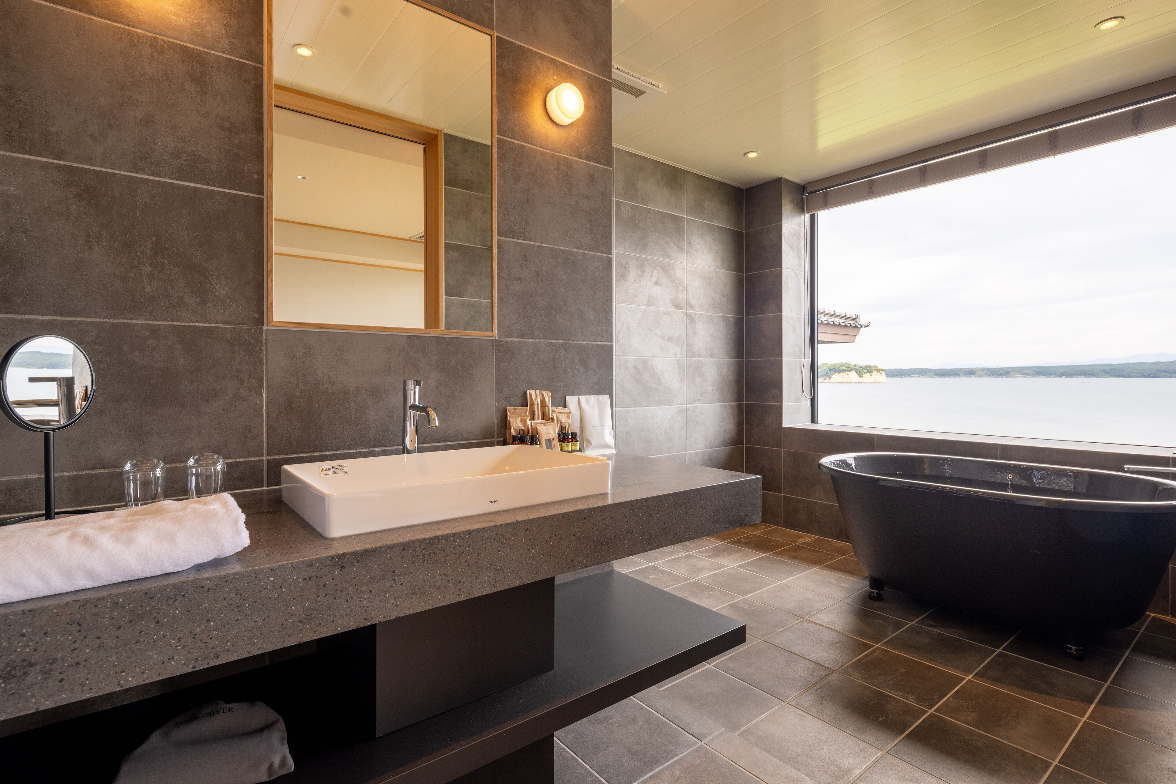 A modern bathroom with a large bathtub, a sink, and a mirror.